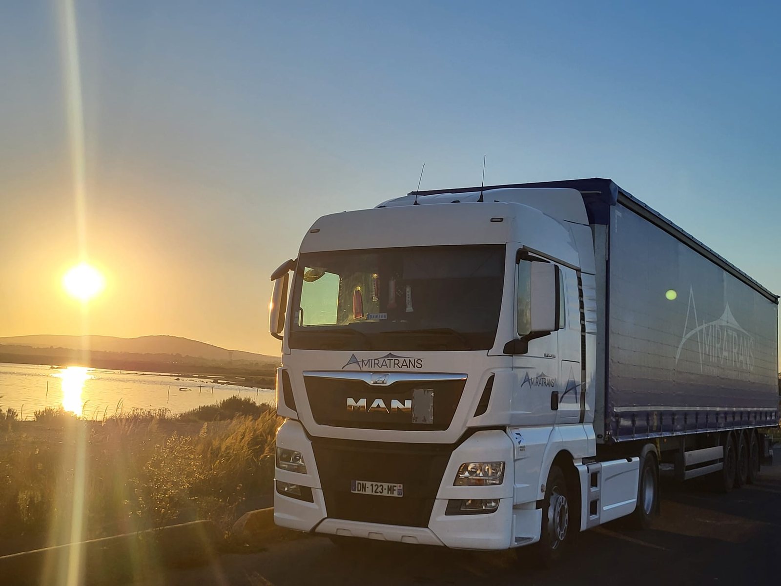 Tracteur Amiratrans au coucher de soleil sur un plan d'eau