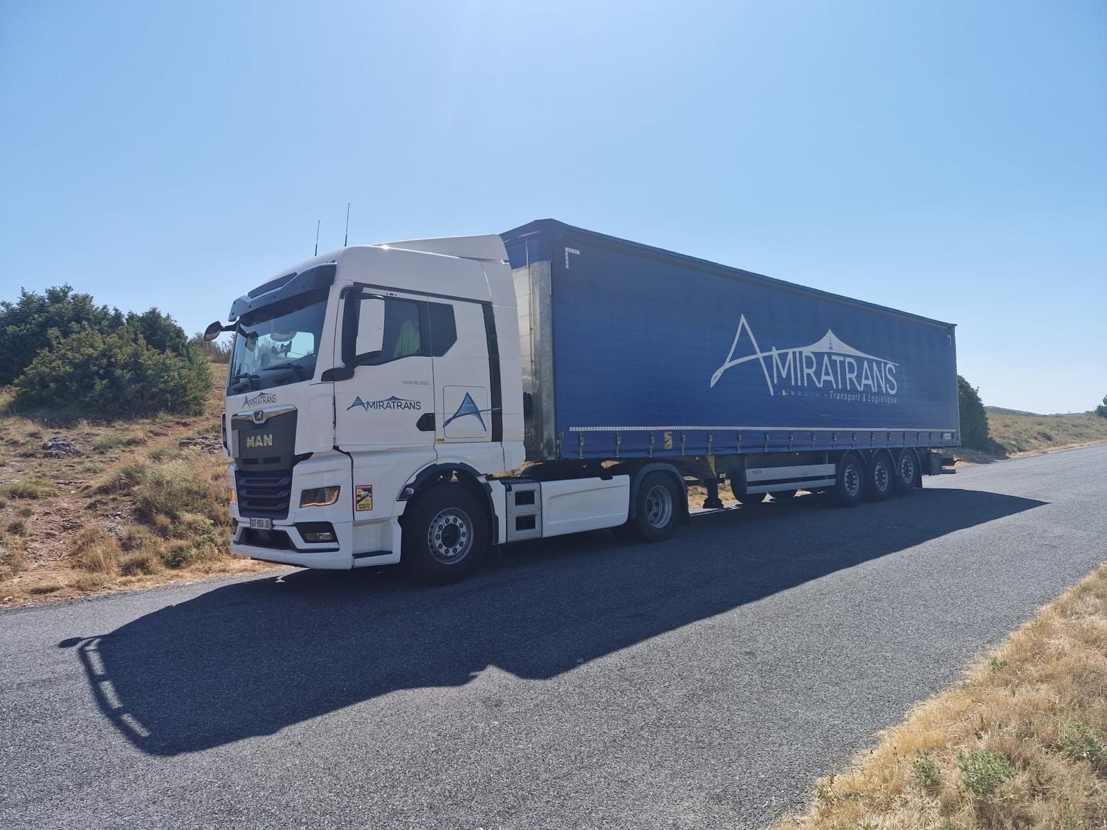 Ensemble Amiratrans avec semi-remorque bâchée bleue sur route de campagne